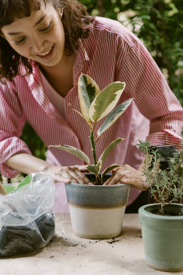 Woman happily tending potted plants outdoors in a casual home gardening setting.